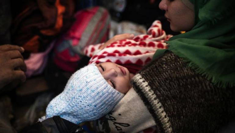 A woman holds a young child as migrants and refugees take shelter near the western Serbian village of Berkasovo, near the Serbia-Croatia border on October 19, 2015 (AFP Photo/Andrej Isakovic) 